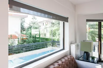 a large window in a living room with a view of a pool at Sol Residence - Private Pool Gym Glyfada in Athens