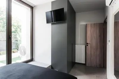 a bedroom with a bed and a tv on the wall at Sol Residence - Private Pool Gym Glyfada in Athens