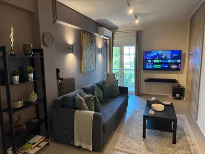a living room with a couch and a flat screen tv at Charming apartment in Glyfada in Athens
