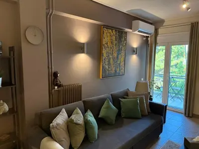 a living room with a blue couch with green pillows at Charming apartment in Glyfada in Athens