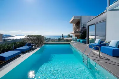 a swimming pool with blue chairs next to a house at Stefano's Villa Lagonissi in Lagonissi