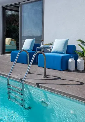 a blue couch sitting next to a swimming pool at Stefano's Villa Lagonissi in Lagonissi