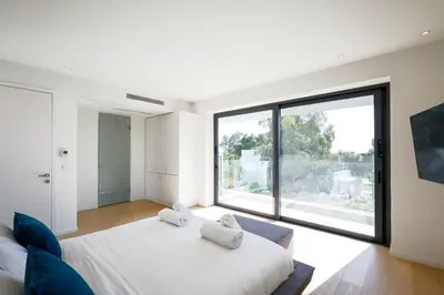 a white bedroom with a large window and a bed at Ellinikon Luxury Apartment in Athens