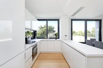 a white kitchen with a long counter and windows at Ellinikon Luxury Apartment in Athens