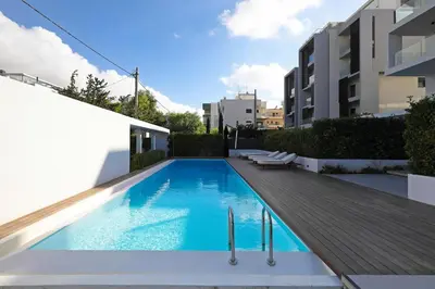 a swimming pool with a wooden deck next to a building at Ellinikon Luxury Apartment in Athens