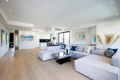 a large living room with white furniture and blue pillows at Ellinikon Luxury Apartment in Athens