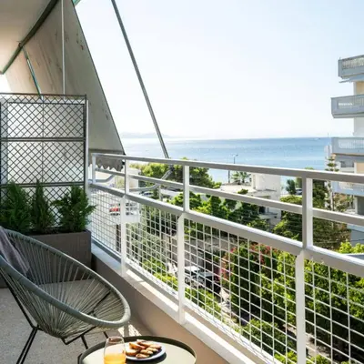 a balcony with a chair and a view of the ocean at 2-BD Luxury Apt Sea View Balcony near the beach in Athens