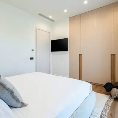 a bedroom with a white bed and a flat screen tv at 2-BD Luxury Apt Sea View Balcony near the beach in Athens