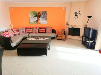 a living room with a couch and a tv at Angela's Home (Near Athens Airport) in Spáta