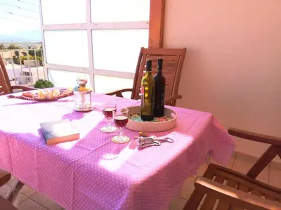 a pink table with a bottle of wine and glasses at Angela's Home (Near Athens Airport) in Spáta
