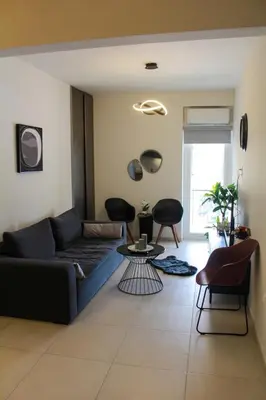 a living room with a blue couch and chairs at AIOLOS GLYFADA super lux suite 5 sea view in Athens