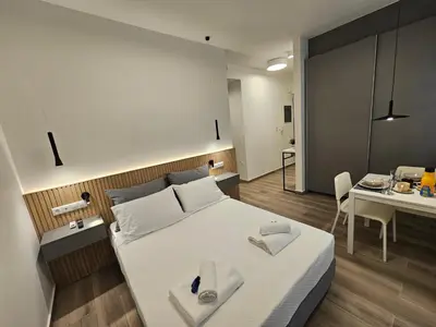 a bedroom with a white bed and a table with a chair at Platon Stylish Apartment in Athens