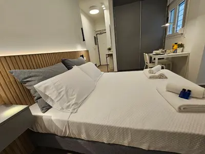a large bed with white sheets and pillows on it at Platon Stylish Apartment in Athens