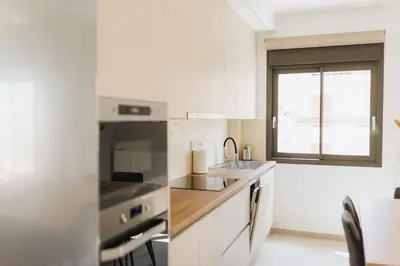 a white kitchen with a sink and a stove at Lavish condo in Athens Riviera in Athens