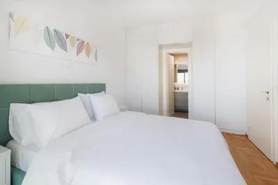 a white bed with white pillows in a bedroom at Lavish condo in Athens Riviera in Athens