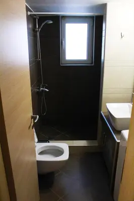 a bathroom with a toilet and a sink and a window at AIOLOS VOULA near the sea apartment in Athens