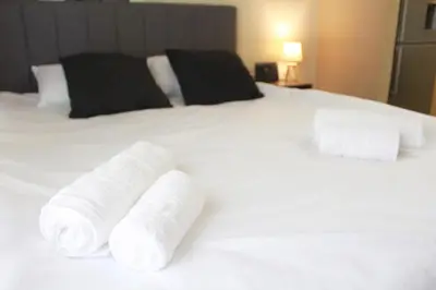 a pile of rolled towels on a white bed at AIOLOS VOULA near the sea apartment in Athens
