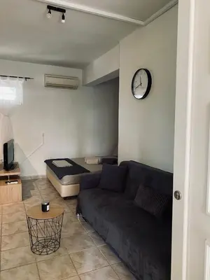 a living room with a couch and a clock on the wall at Cosy House Glyfada in Athens