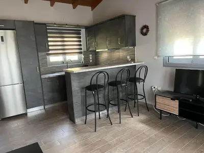 a kitchen with three bar stools and a counter at Zinia House in Porto Rafti
