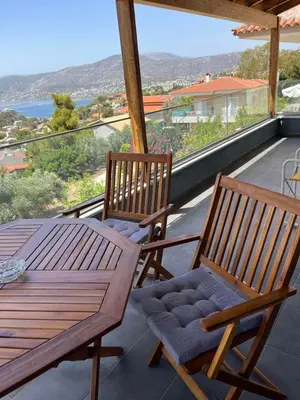 two wooden chairs and a table on a balcony at Zinia House in Porto Rafti