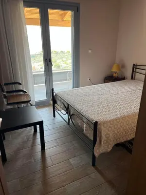 a bedroom with a bed and a chair and a window at Zinia House in Porto Rafti