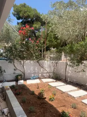 a garden with a fence and a tree with red flowers at Παραθαλάσσιο στούντιο με κήπο in Saronida