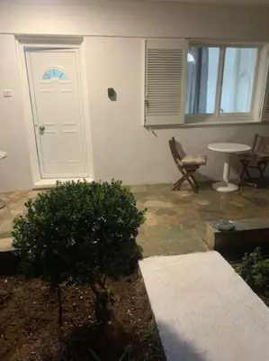 a house with a white door and a table and chairs at Παραθαλάσσιο στούντιο με κήπο in Saronida