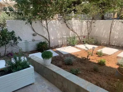 a garden with a retaining wall and some plants at Παραθαλάσσιο στούντιο με κήπο in Saronida