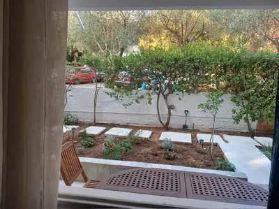 a view of a garden from a window at Παραθαλάσσιο στούντιο με κήπο in Saronida