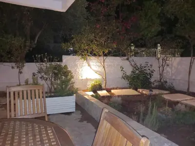 a garden at night with a bench and a fence at Παραθαλάσσιο στούντιο με κήπο in Saronida