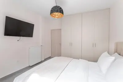 a white bedroom with a bed and a flat screen tv at Afroditi Suite in Athens