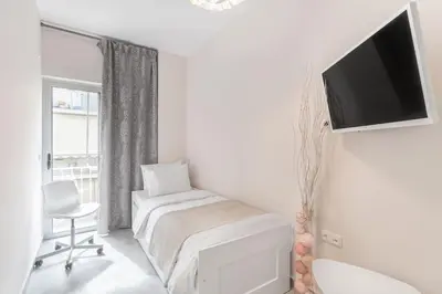 a white room with a bed and a tv on a wall at Afroditi Suite in Athens