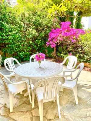 a table with four chairs and a vase with flowers on it at 2 Bedroom, Sea Side Retreat Saronida in Saronida