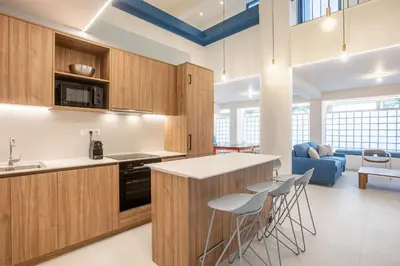 a kitchen with wooden cabinets and bar stools at Kallithea Apartments by Olala Homes in Athens
