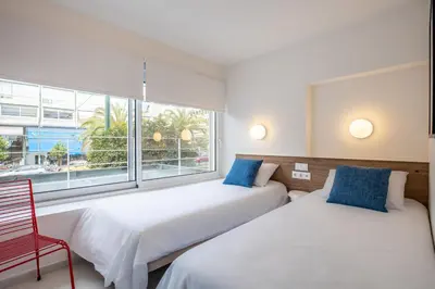 two beds in a room with a window and a red chair at Kallithea Apartments by Olala Homes in Athens