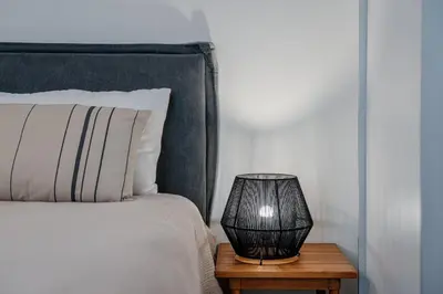 a lamp on a wooden table next to a bed at Bella in Athens