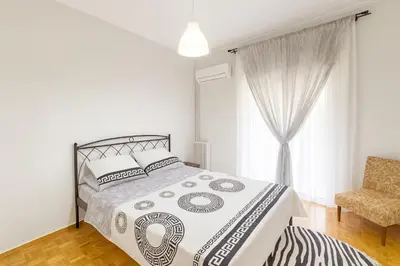 a bedroom with a bed and a chair and a window at Sunny Dream House in Piraeus
