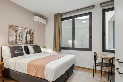 a bedroom with a bed and a desk and windows at Limehome Athens Solonos City Center in Athens