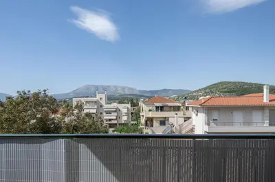 a bird flying over a fence in a city at Nesto Athens Airport Den in Spáta