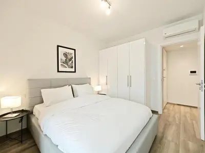 a white bedroom with a large bed and two lamps at Kapodistriou by Verde Apartments in Athens