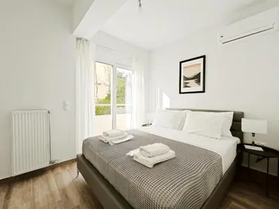 a white bedroom with a bed with two towels on it at Kapodistriou by Verde Apartments in Athens