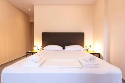 a bedroom with a large white bed with towels on it at Mini Suites Near Athen's Airport Free Shuttle From and to Athen's Airport in Spáta