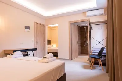 a hotel room with two beds and a chair at Mini Suites Near Athen's Airport Free Shuttle From and to Athen's Airport in Spáta