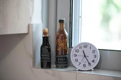 two bottles of alcohol and a clock on a window sill at Ruby’s House in Athens