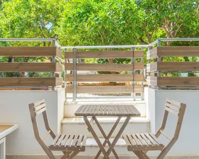 two wooden chairs and a table on a balcony at Voula's Secret Garden Studio in Athens