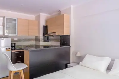 a bedroom with a bed and a kitchen with a desk at Voula's Secret Garden Studio in Athens