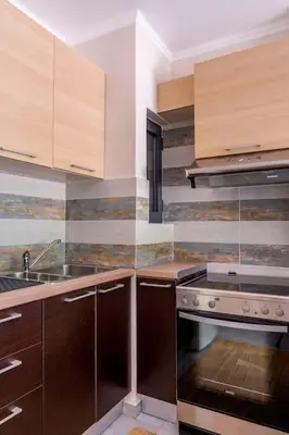 a kitchen with wooden cabinets and a stove top oven at Voula's Secret Garden Studio in Athens