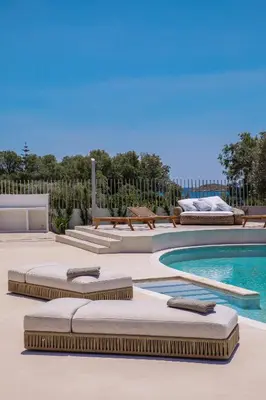 a pool with chaise lounges next to a swimming pool at Seafront Athens Riviera Lagonisi Villa in Lagonissi