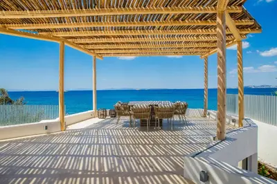 a deck with a table and chairs on the beach at Seafront Athens Riviera Lagonisi Villa in Lagonissi
