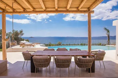 a patio with a table and chairs and a pool at Seafront Athens Riviera Lagonisi Villa in Lagonissi
